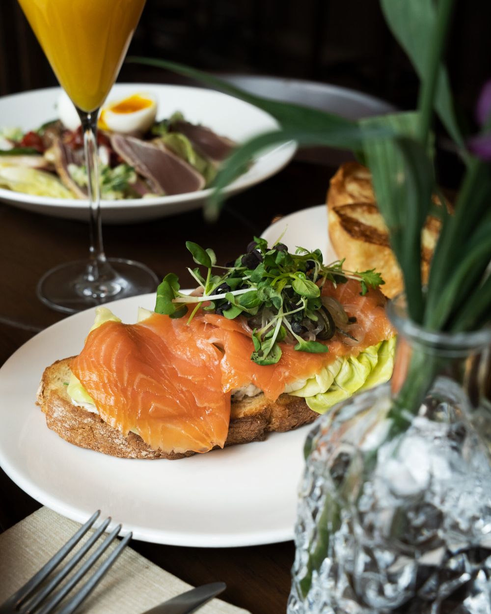 Gerookte zalm op toast met een salade en een glas verse jus d'orange