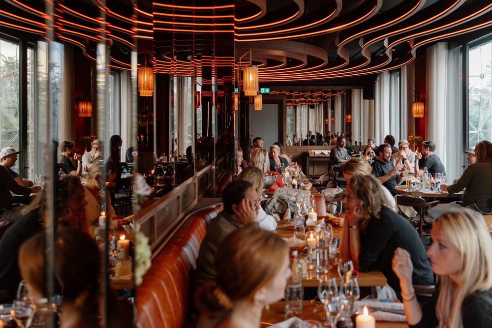 Een drukke avond in de Bistro: groepen dineren bij kaarslicht langs de leren bank