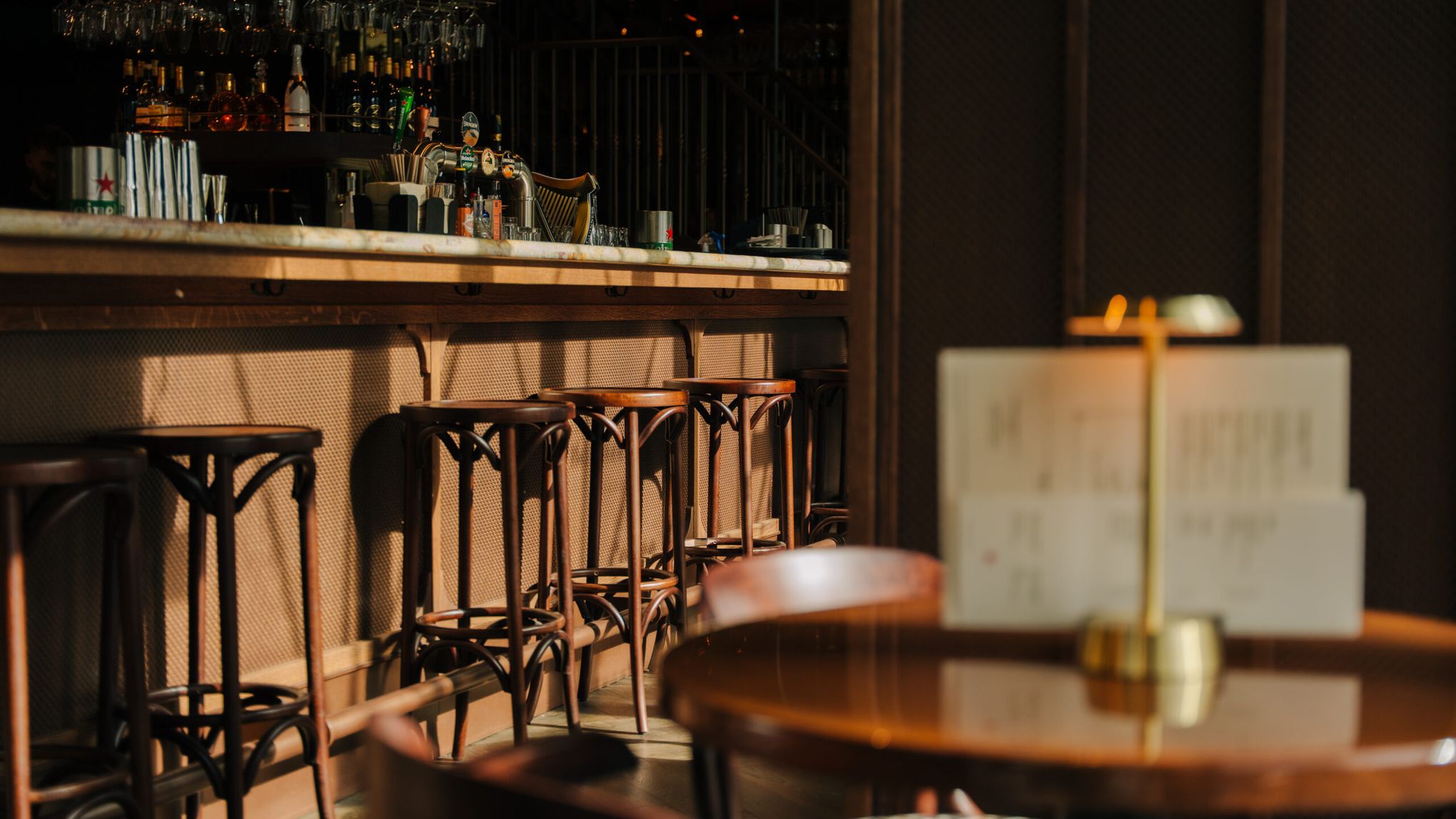 De bar met houten barkrukken, op de voorgrond een messing tafellamp