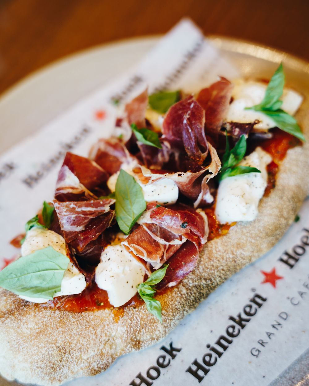 Flatbread met rauwe ham, mozzarella en basilicum op Heineken Hoek-papier