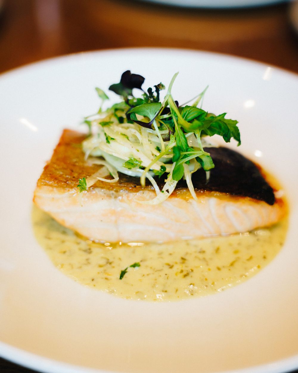 Crispy-skinned salmon fillet topped with fennel and cress in a herb sauce