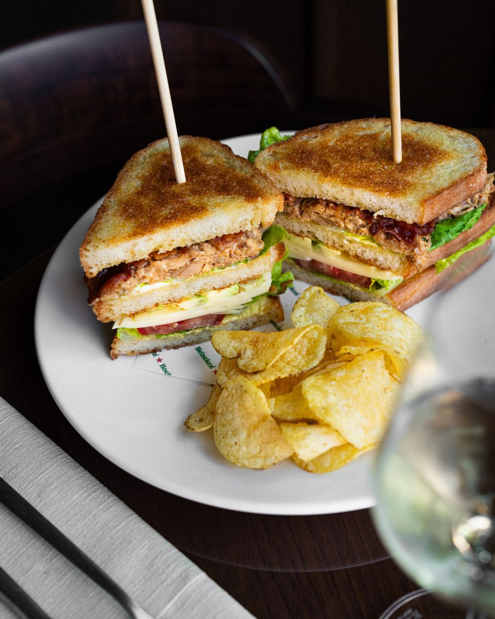 Clubsandwich met prikkers en chips op een wit bord